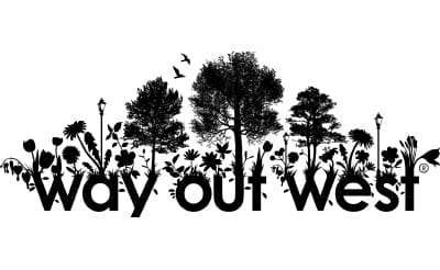 Svart silhuettlogotyp med orden Way out West längst ner, omgiven av vildblommor, träd och lyktstolpar. Fåglar flyger ovanför - en slående design som är perfekt för tillfälliga tatueringar för företag.